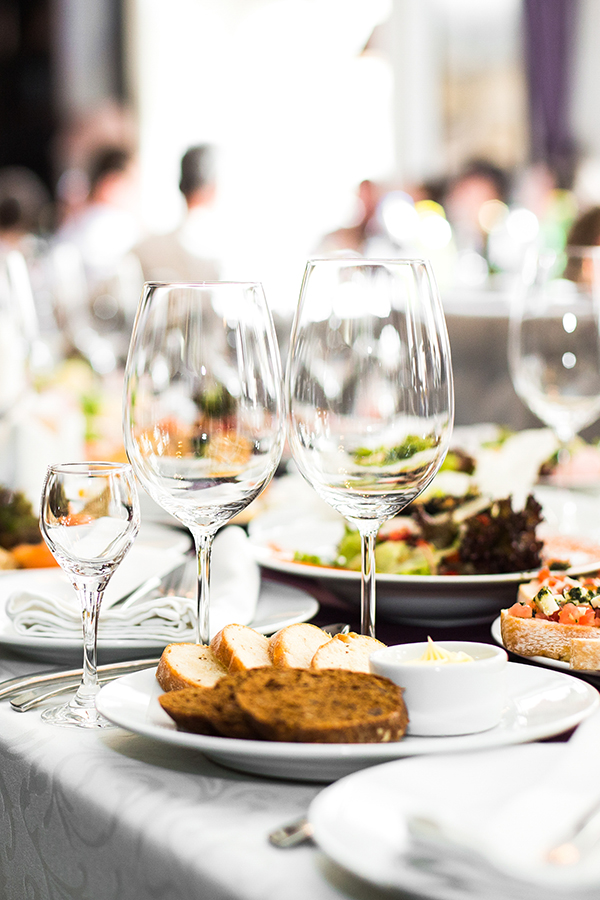 Sparkling glassware stands on long table prepared for wedding di